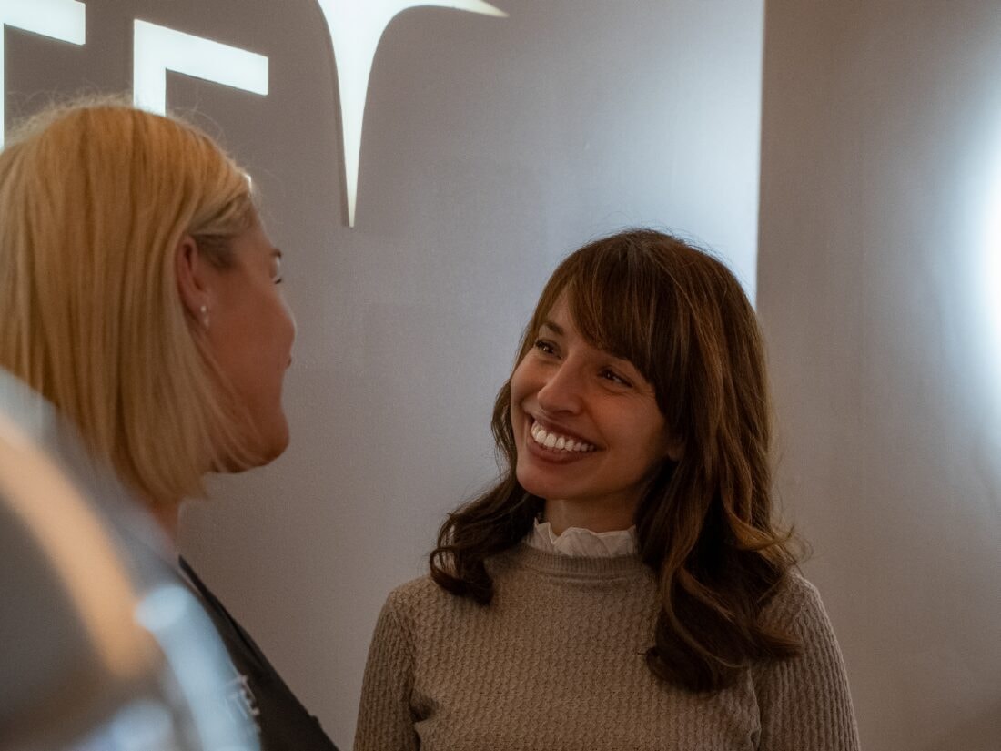 A guest and a member of the WYTE team talking in front of the illuminated brand wall.