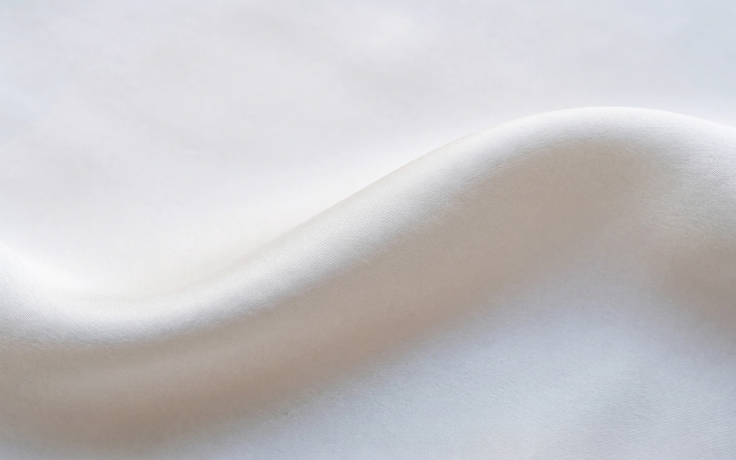 White fabric in a wide shallow wave with a quiet, muted sheen.